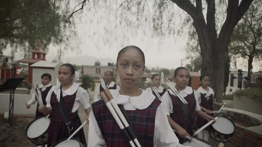 All girl drum group performing outdoors carrying second pair of drumsticks
