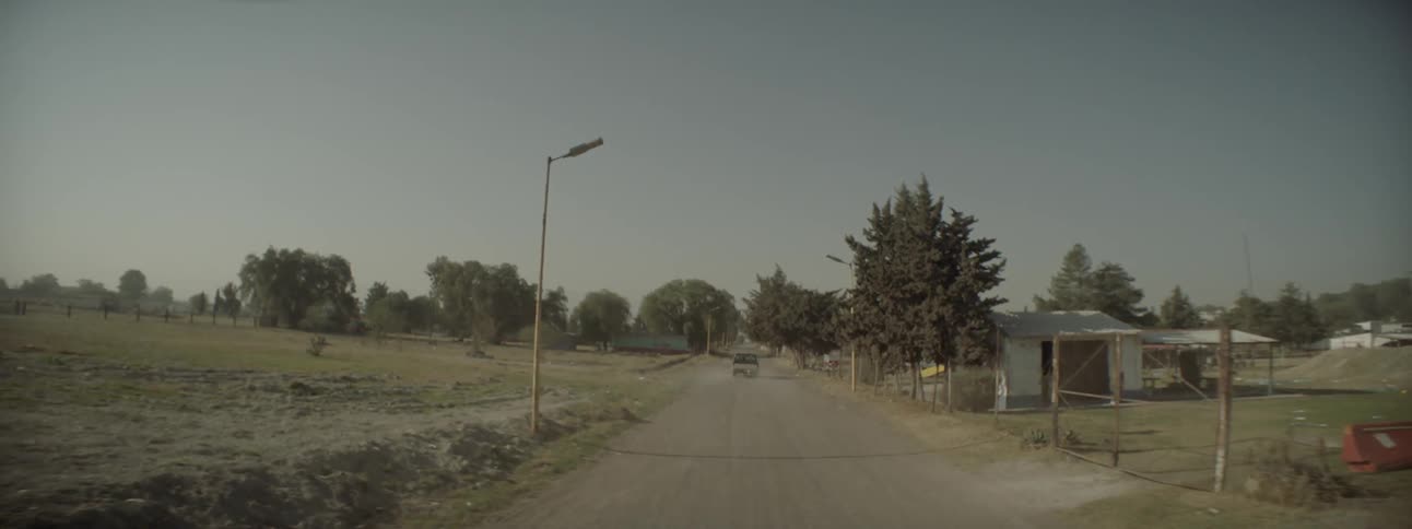 A vehicle drives down a road in a rural village