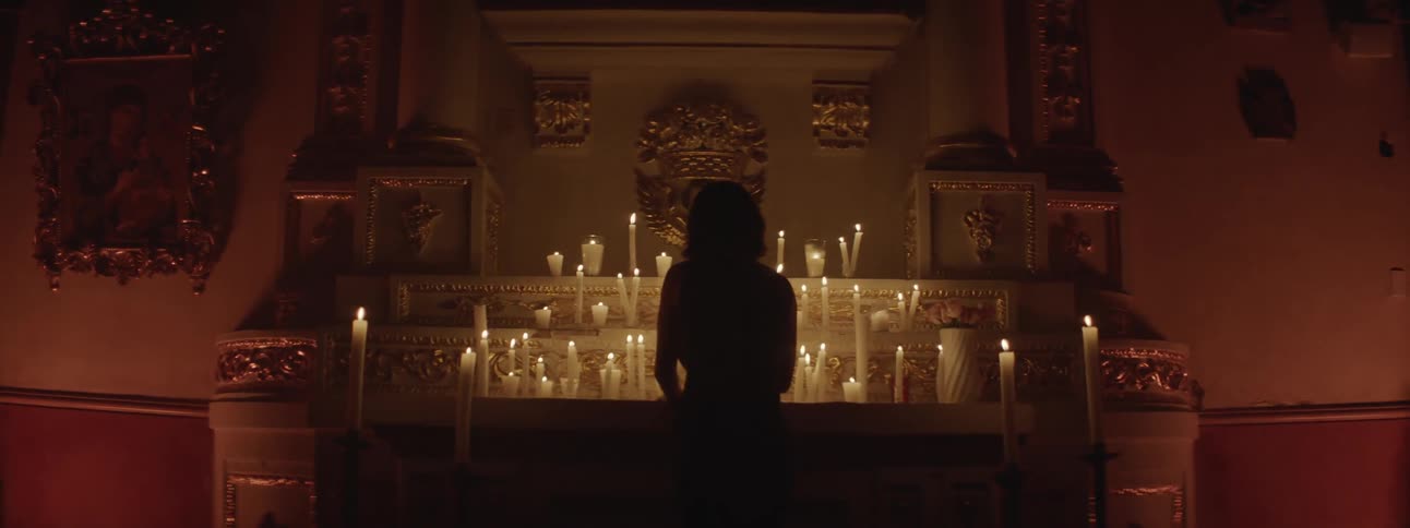 A woman lights candles at an alter