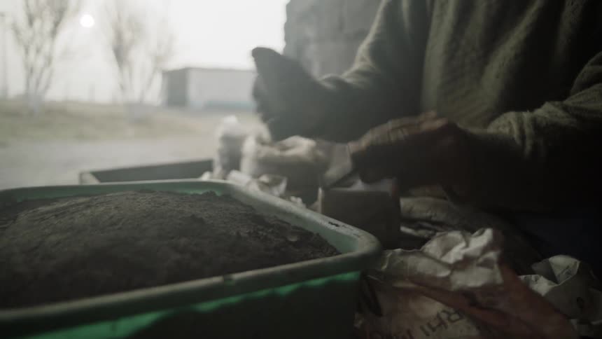 A man puts soil in a container and packs it down