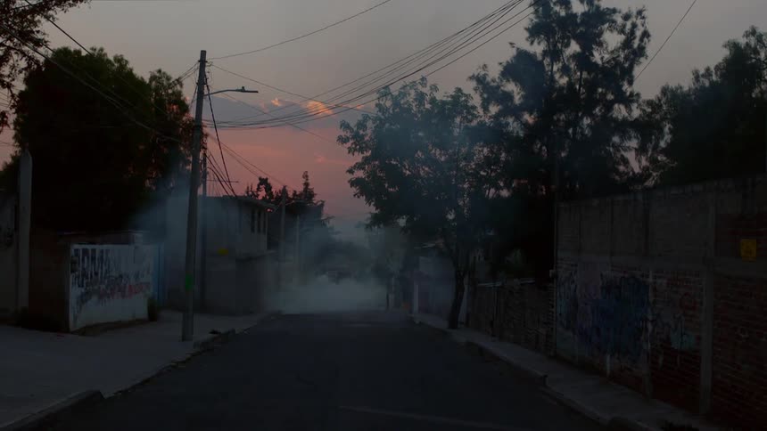 A road engulfed in smoke in a rundown neighborhood