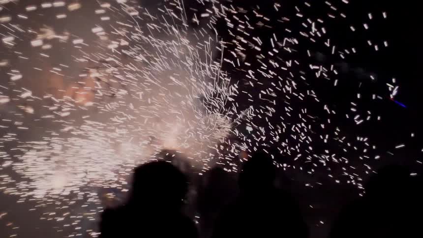 People move back and video as fireworks and sparks explode and burst at night