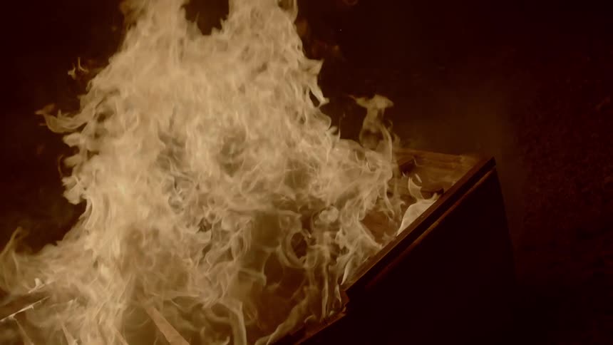 A piece of wooden furniture is engulfed in flames that are burning intensely