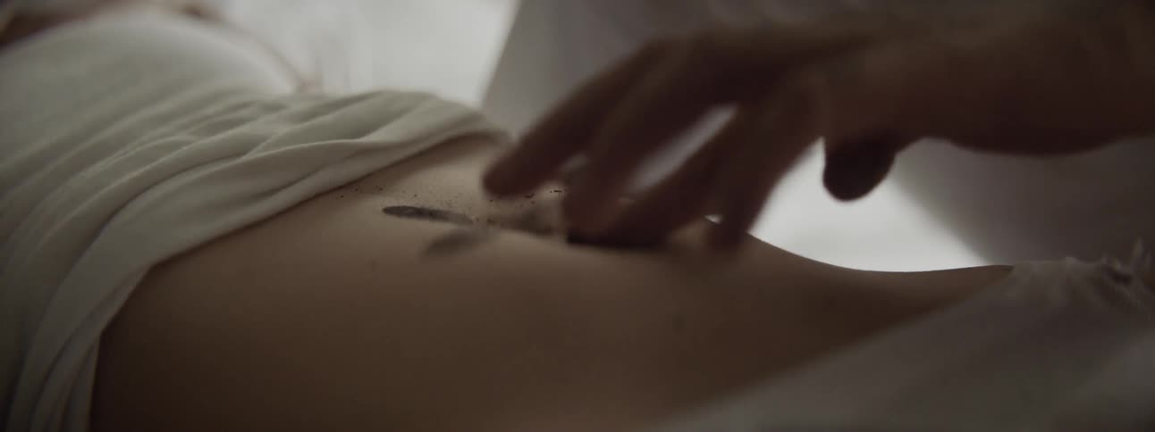A man makes a cross out of dirt on a girls stomach