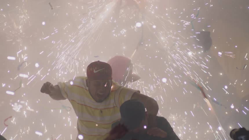 A group of teens jump up and down as sparks fly