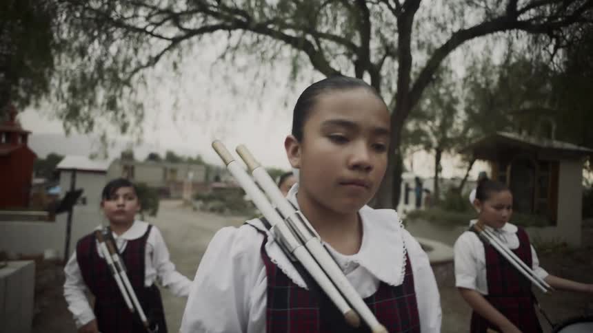 Girls in school uniforms marching and playing drums