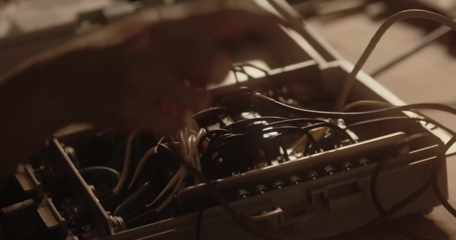 A person is connecting wires in an enclosure