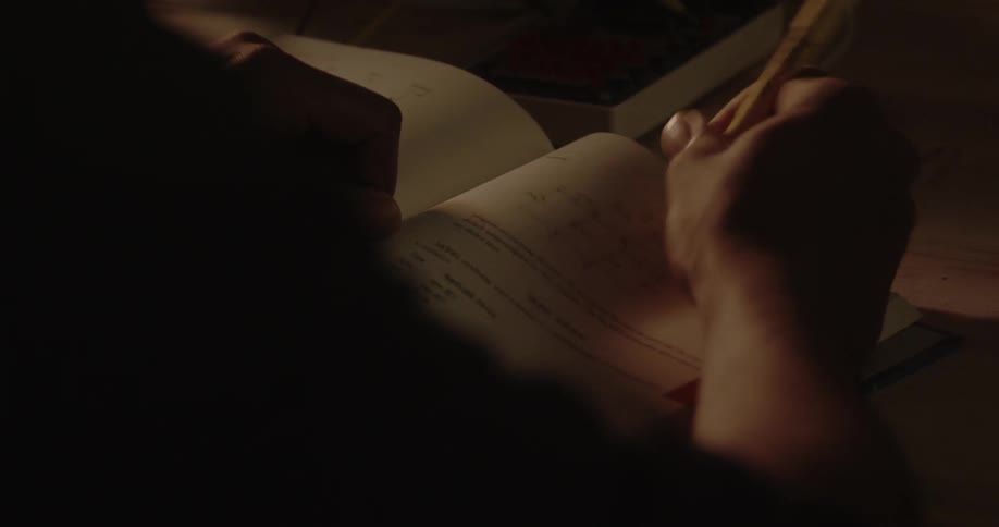 Person writing in a textbook with a highlighter