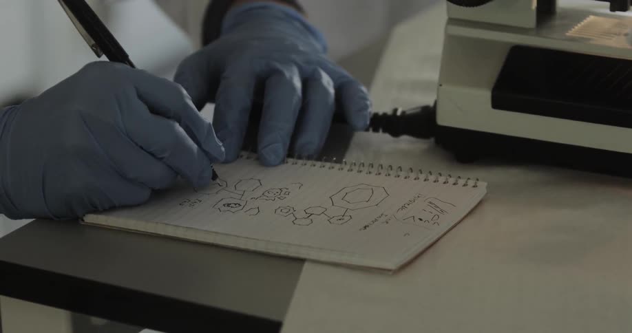 A person with gloves writes in a notebook