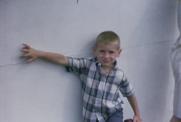 A young boy leaning against a wall next to a woman
