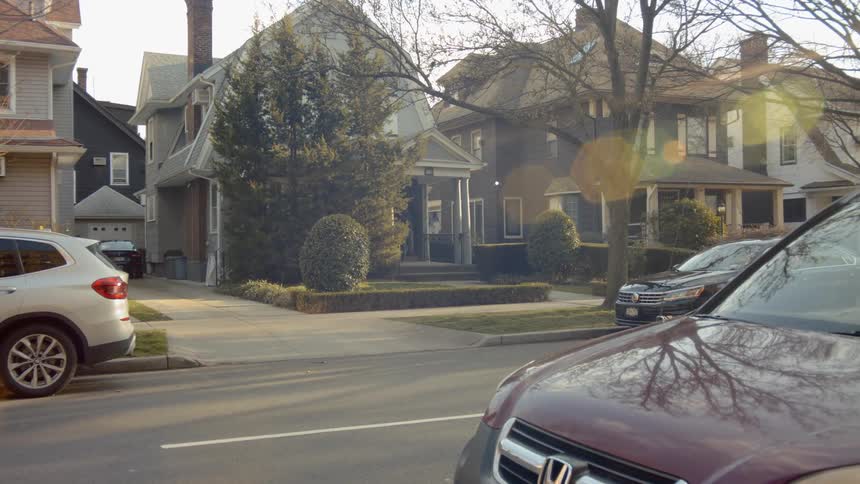 A person carrying a large box onto the porch of a house