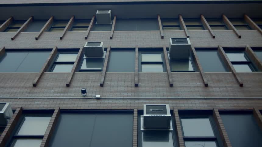 A facade of a building with several air conditioners sticking out of windows