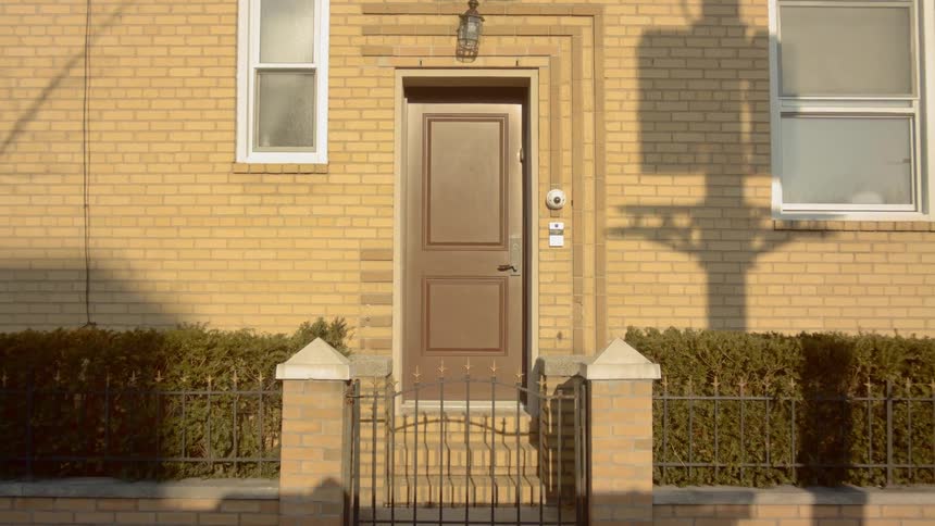 Sun casts shadows on front porch and brick house surface