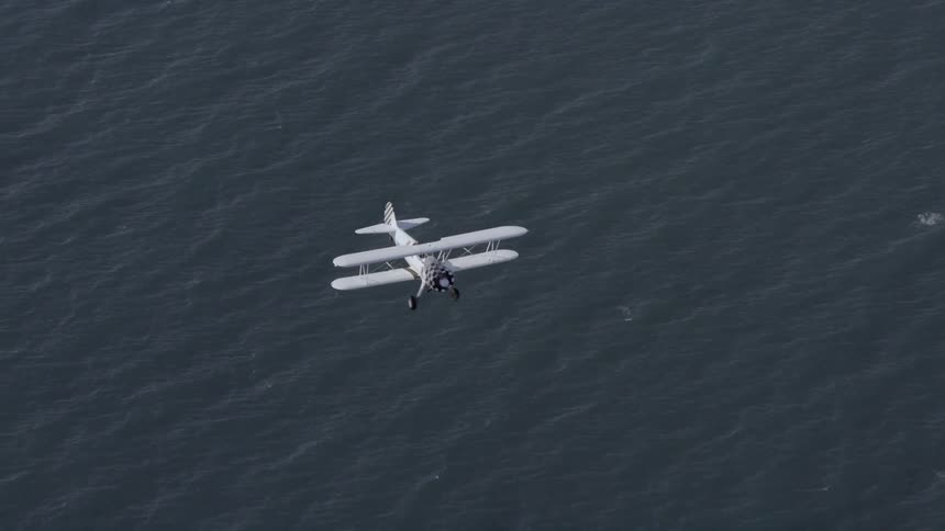 A small plane is flying over the water
