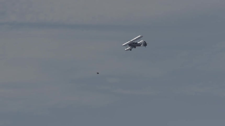 Bi-plane flying against a partly cloudy sky