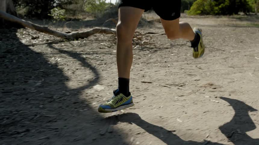 A man is jogging on a dirt path during the day