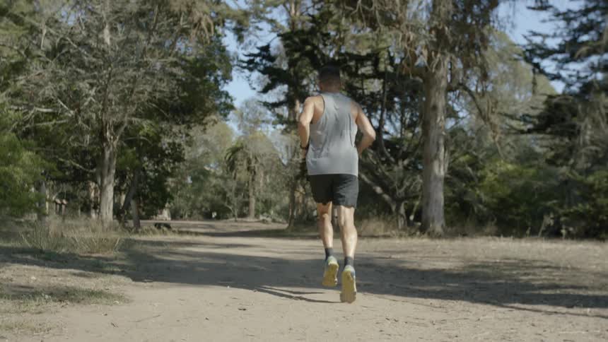 Man jogging a trail through the wilderness on a clear day