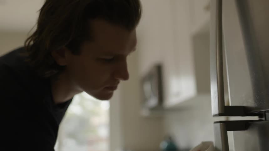 A man is cleaning a fridge in a kitchen