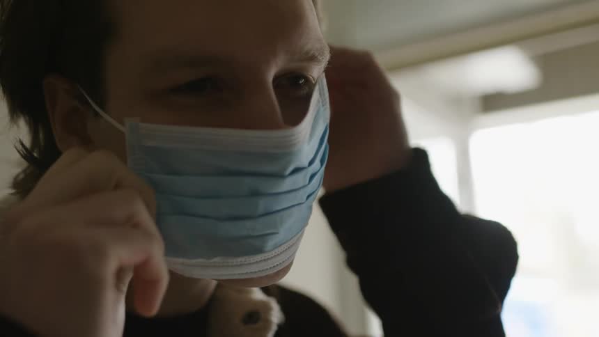A man puts a medical mask over his nose and mouth