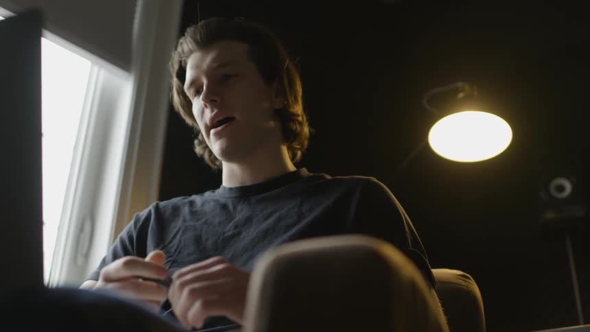 A man speaking while sitting in front of a laptop