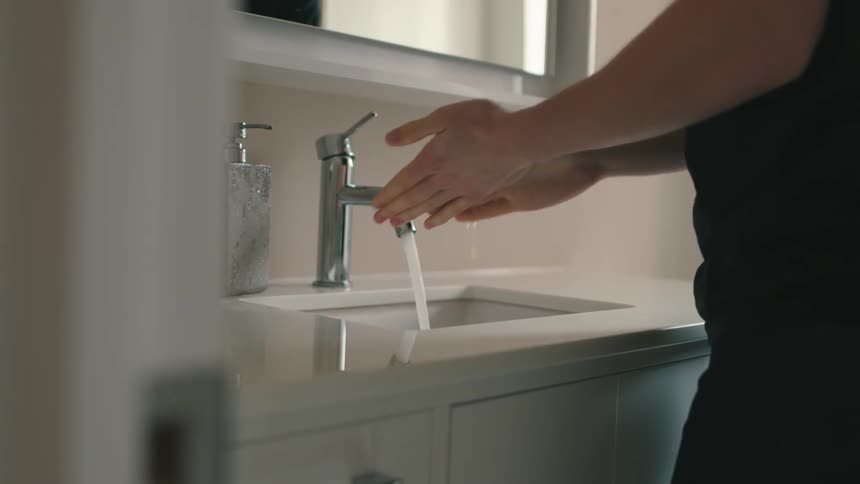 A person using a soap dispenser before lathering their hands in soap