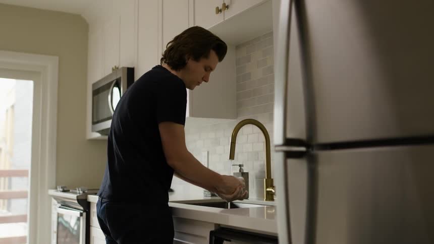 A man washing his hands in a kitchen faucet