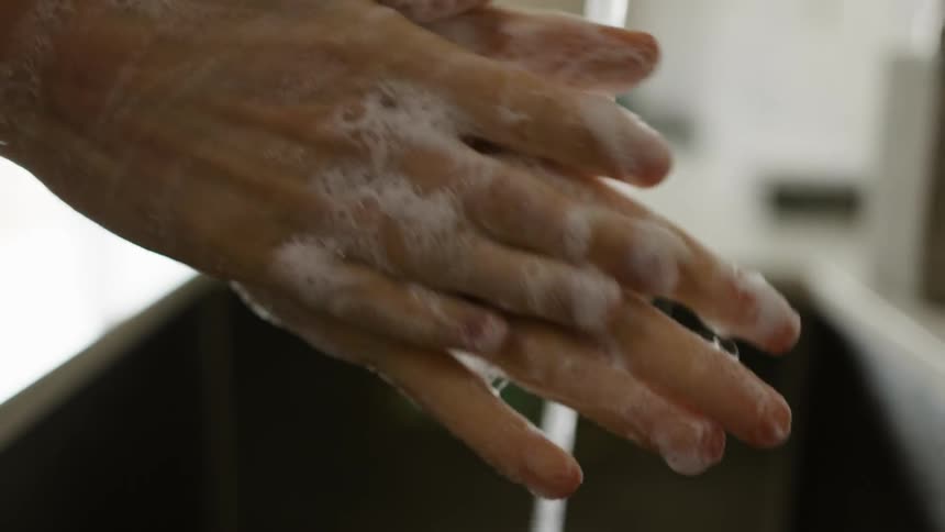 A person is washing their hands in the kitchen sink