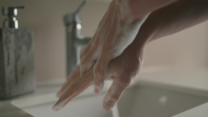 A person is washing their hands with soap by a sink