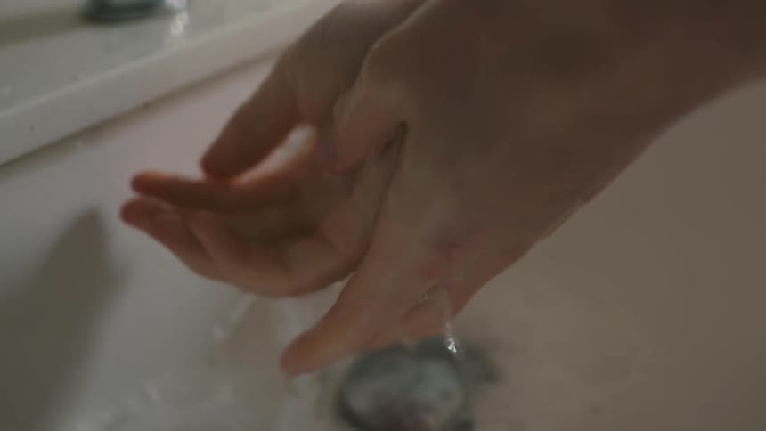 A person washes their hands in a sink