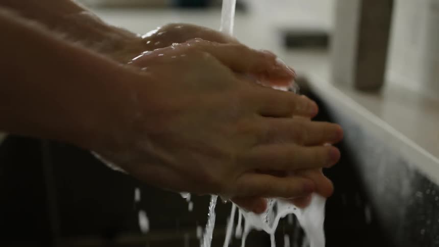 A woman washes her hands in the sink