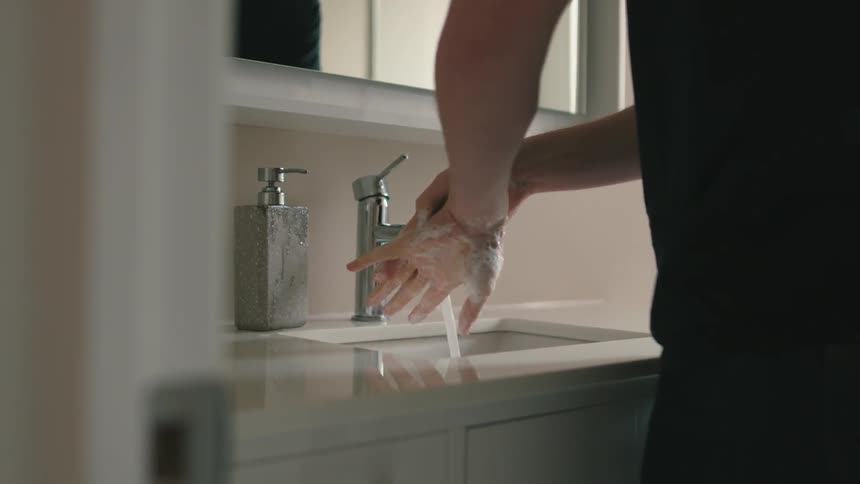 A man washes his hands in a kitchen sink