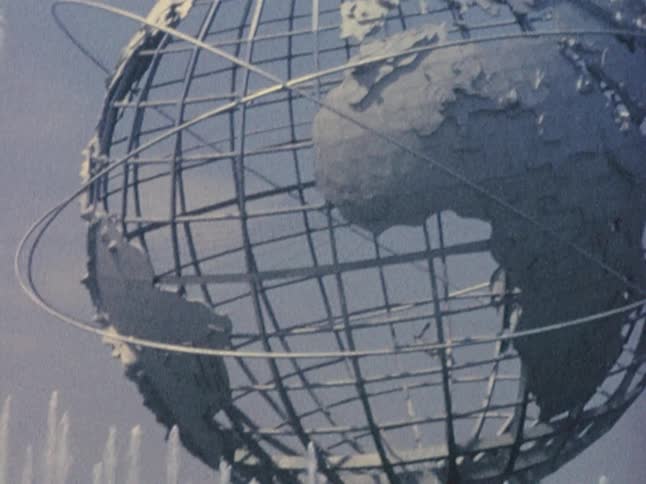 A woman walks near a metal globe with her son