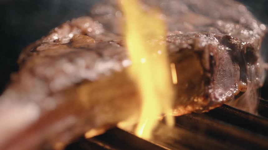 A steak being engulfed in flames on a grill