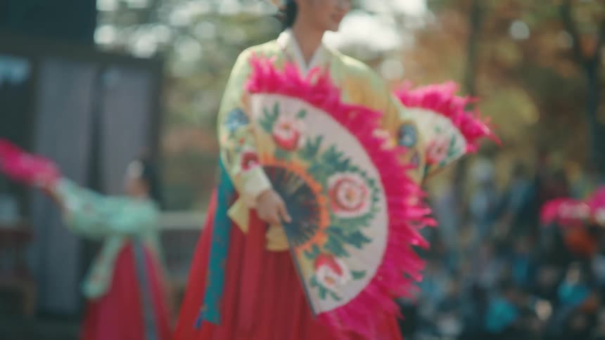 A woman in intricate dress does a fan dance