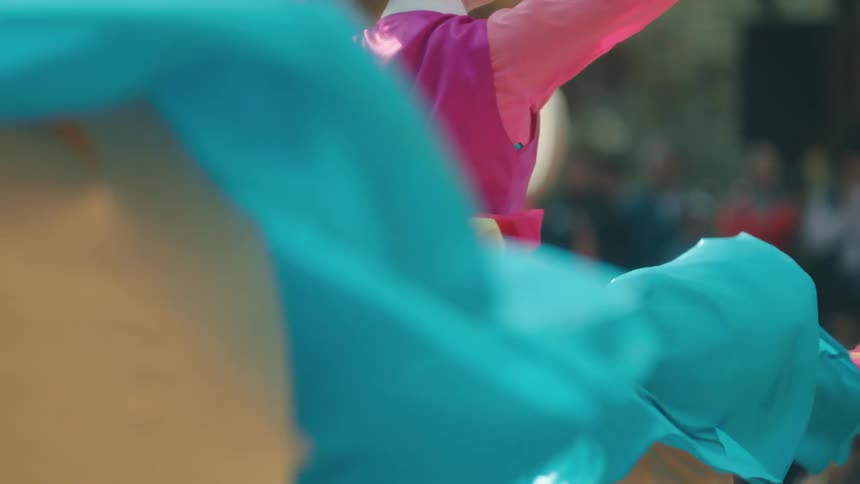 Women in large colorful dresses twirl while dancing