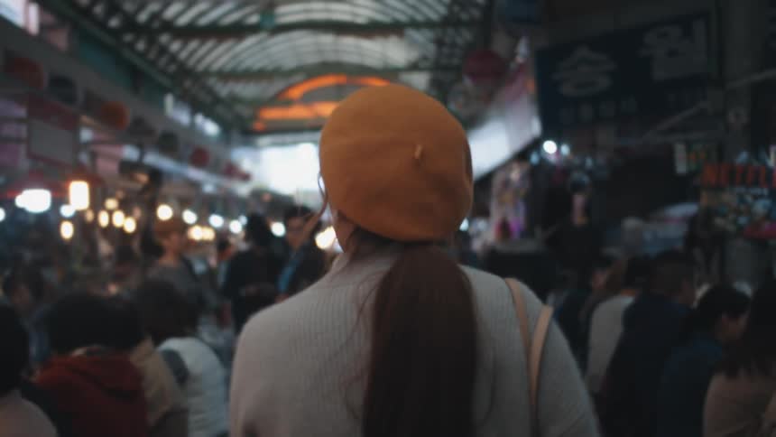 A woman walks through a crowded building with people sitting at counters eating