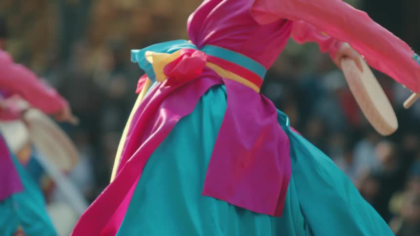 Dancers in colorful dresses perform in a park