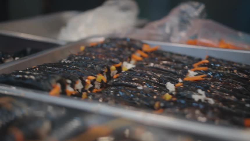 Multiple trays filled with rolled sushi