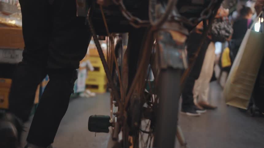 Person walks bicycle through crowded market