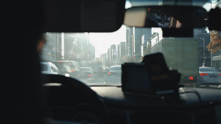 The windshield and dashboard of a car traveling through heavy downtown traffic