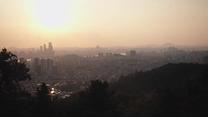 From high atop a hill a sprawling city scape can be seen fill with many buildings and sky scrapers