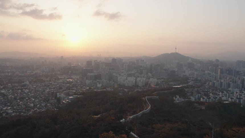 A city with green space and a wall between two sections and a hill on the horizon at sunrise