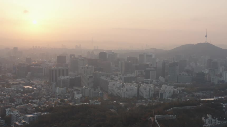A large city skyline on a foggy day during sunrise