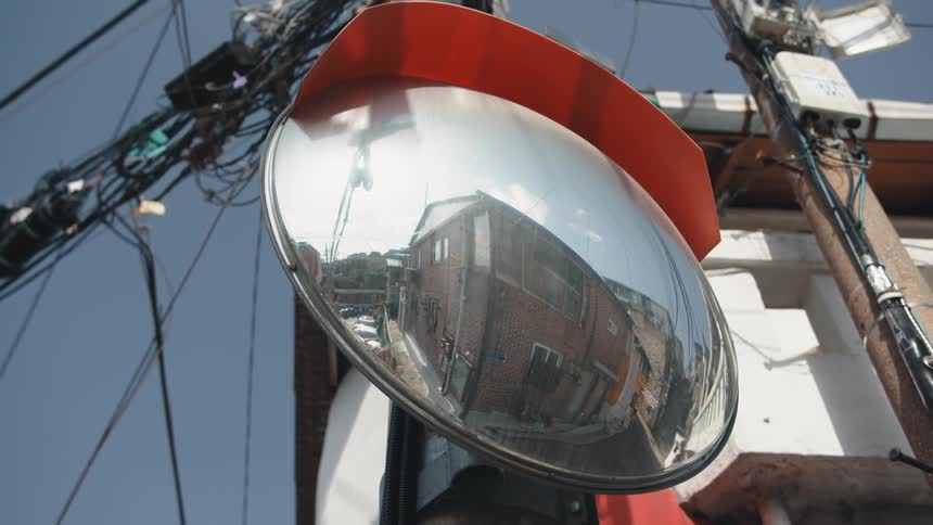 A street mirror reflects the building and road surroundings