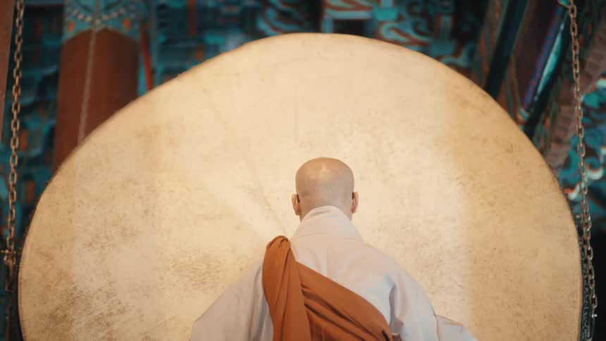 A monk striking a ceremonial drum at night