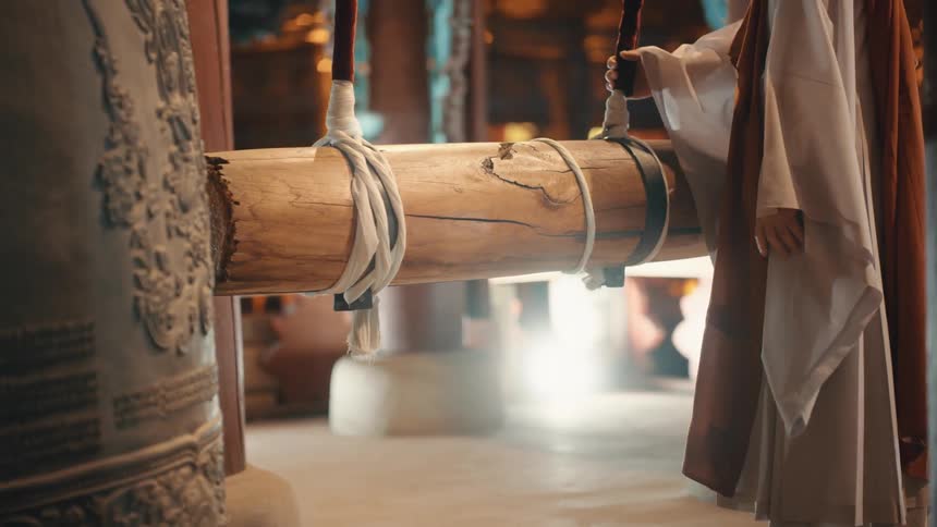 A person ina robe pushes a large wooden log towards an object