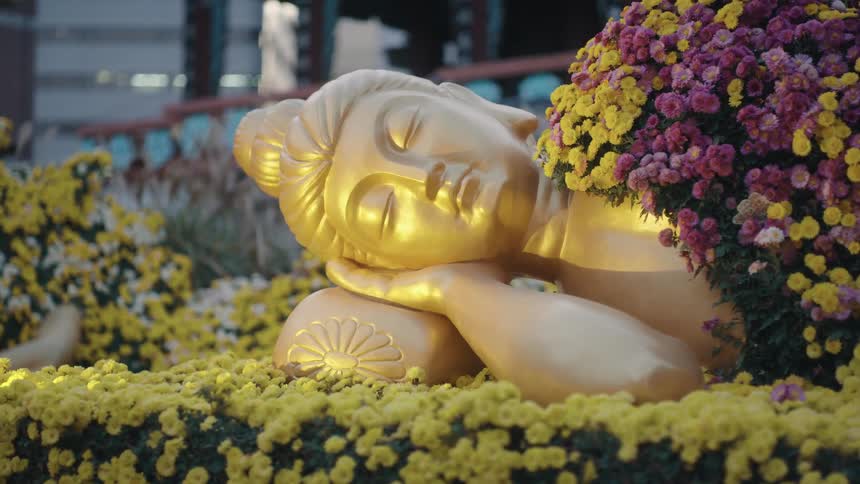 A gold buddhist statue covered in flowers