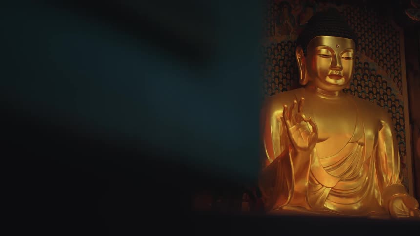 A large golden buddha statue against a lattice wall