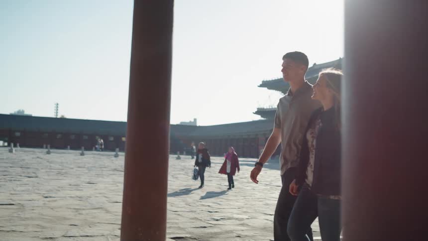 A man has his arm around his girlfriend as they walk past a building
