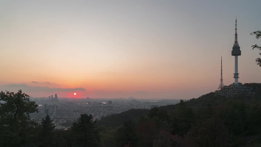 A tower on a hill overlooking a distant city